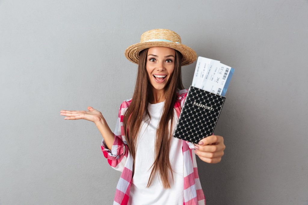 mujer feliz con sombrero de paja, pasaporte, visado y tiquetes de avion